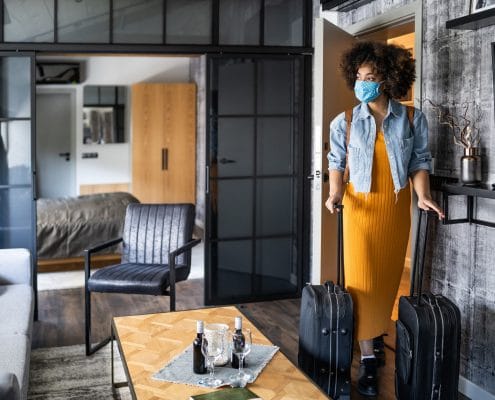 Beautiful afro woman with protective face mask arriving in hotel room
