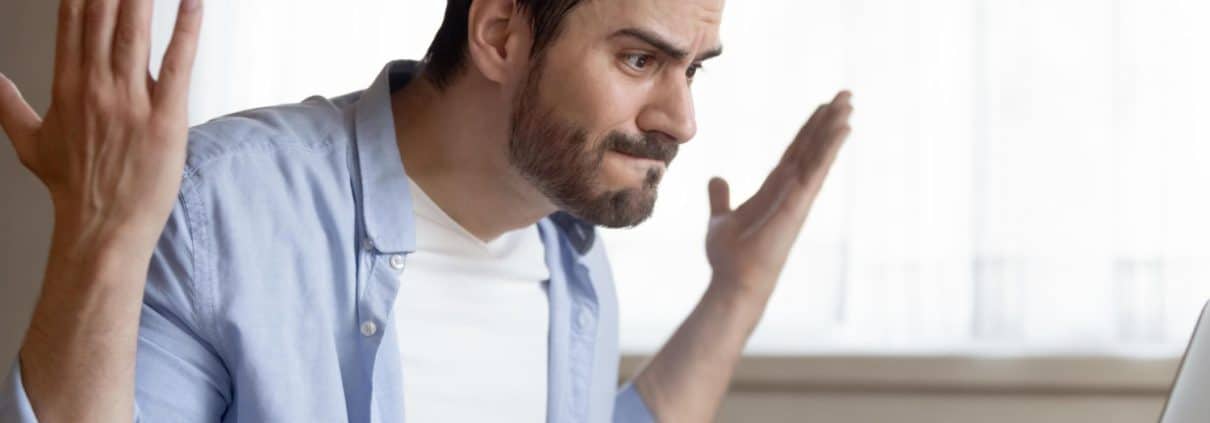 Angry caucasian young male work on laptop at home