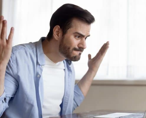 Angry caucasian young male work on laptop at home